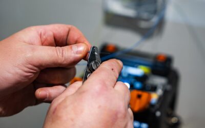 Kuvassa näkyy henkilö, joka käyttää työkalua työskennelläkseen valokuitukaapelin parissa.
