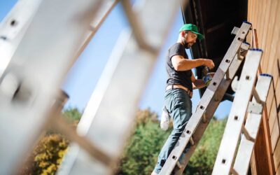 Henkilö on kiivennyt tikapuille on aloittamassa kodin ulkoseinän maalausta. Hänellä on kädessään maalipurkki ja maalisuti.