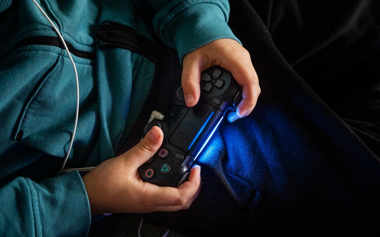 Nuoren henkilö pelaamassa Playstation-konsolipeliä.