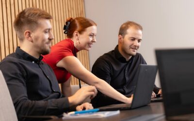 Kolme Oulun Seudun Sähkön työntekijää on kokoontunut pöydän ääreen kannettavien tietokoneiden kanssa.