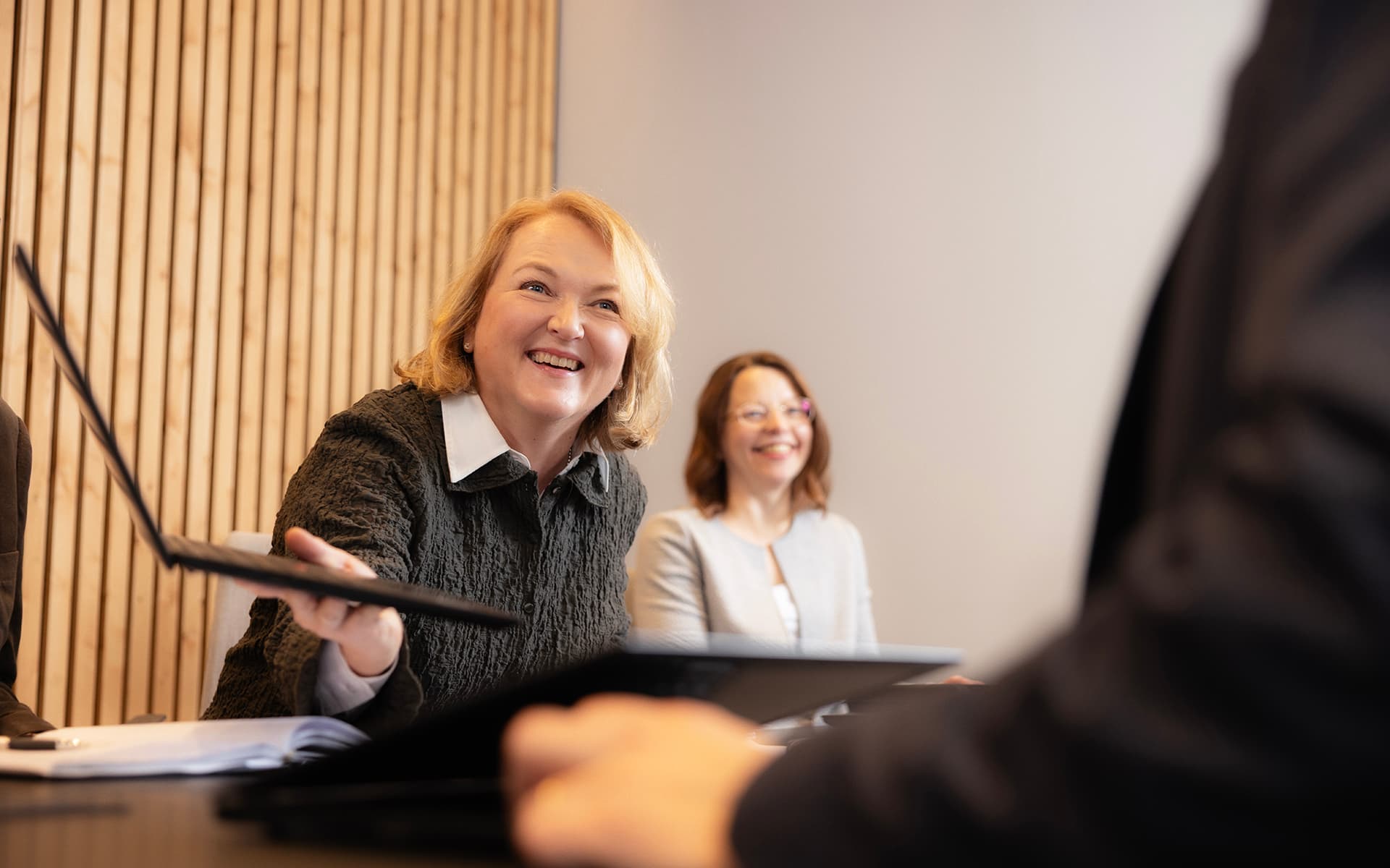 Iloiset Oulun Seudun Sähkön työntekijät keskustelevat kokouksessa kannettavien tietokoneiden äärellä.