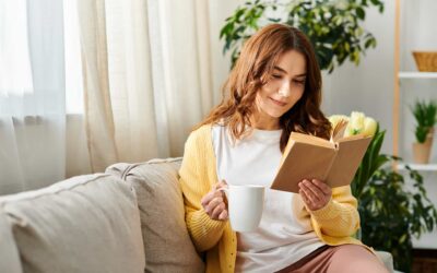 Henkilö istuu rennosti sohvalla lukien kirjaa ja pitäen kädessään kahvikuppia. Taustalla näkyy ohuiden verhojen peittämä ikkuna, useita viherkasveja ja kirjahylly.